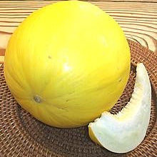 Yellow watermelon with a slice on a woven mat